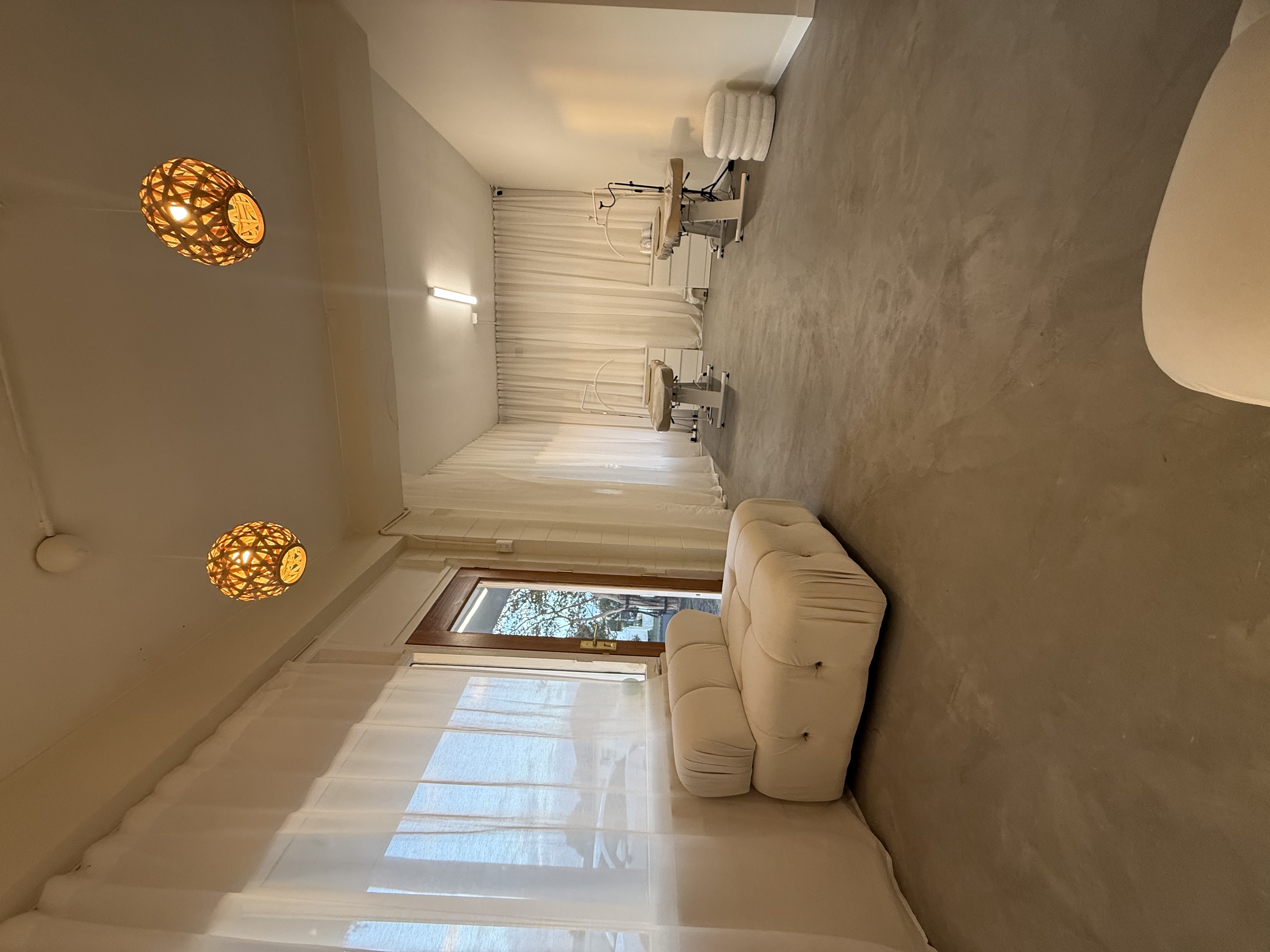 The Bhava Beauty studio — rattan pendants, cream sofa, and treatment room beyond